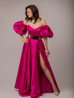 Elegant woman wearing a fuchsia debs dress with dramatic puff sleeves and a high slit, posing confidently in a glamorous setting.